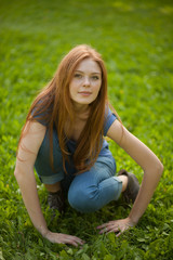 Naklejka na ściany i meble beautiful red-haired girl sitting on grass