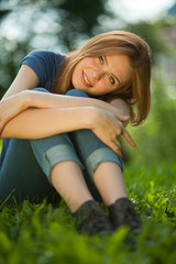 Naklejka na ściany i meble beautiful red-haired girl sitting on grass