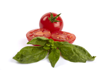 Eine ganze und zwie halbe Cherrytomaten mit Basilikum