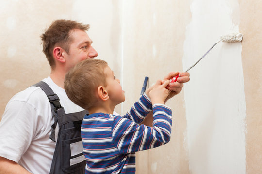 Father painting wall with child