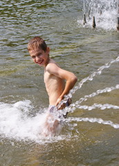Мальчик купается в городском фонтане