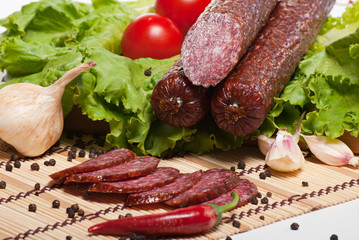 Salami with lettuce, garlic and tomatoes on white background