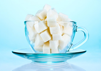 refined sugar in glass cup on blue background