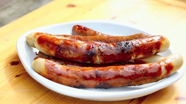 Bratwurst wird mit einer Zange genommen