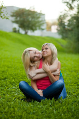 Two girls sitting on the grass, embracing