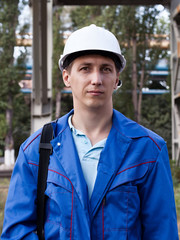 Young handsome man constructor in white hardhat and blue uniform