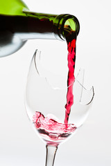 Red wine pouring to the broken glass