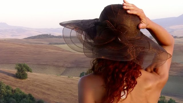 paesaggio di toscana e donna con un cappello