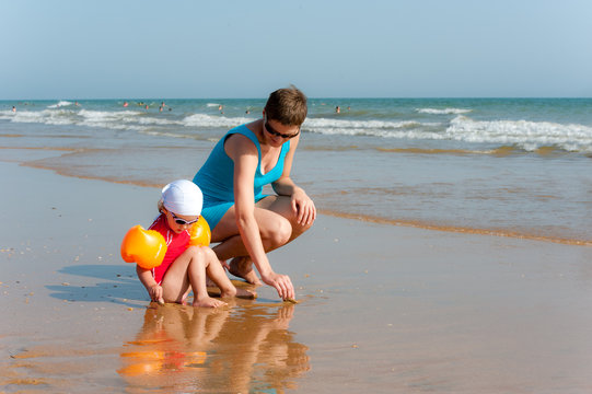 Mother and baby are looking for shell