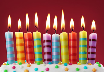 Ten colorful candles on red background