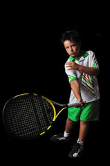 Tennis boy playing forehand isolated in black