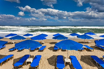 Blue parasols at an empty, stormy beach