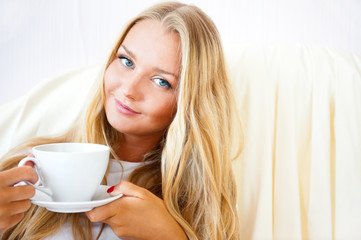 Young woman at home sipping tea or coffee from a cup