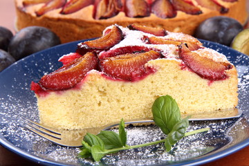 Plum pie and plums decorated with mint on a wooden background