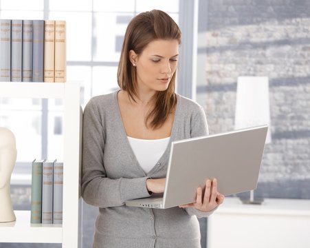 Pretty woman by bookshelf with computer