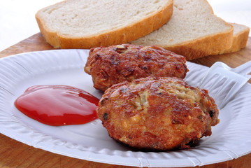Frikadellen mit Ketchup auf einem weißen Pappteller