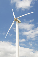 Wind turbine against a sky blue background with clouds