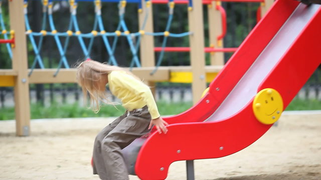 Little twin girls sliding down the chute