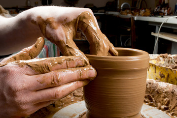 hands of a potter, creating an earthen jar on the circle