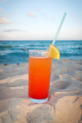 Tequila sunrise drink on Caribbean beach at sunset