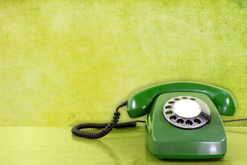 old  scratched phone against green wall background.