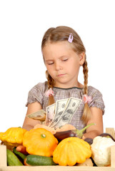 Fototapeta premium Sad little girl counts money and vegetables isolated on the whit