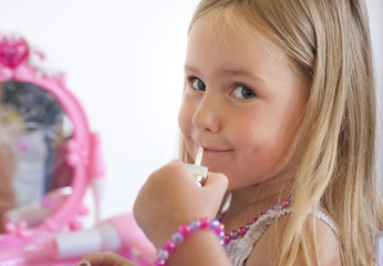 little girl pretending to put on lip gloss