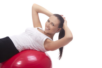 Fototapeta na wymiar pretty brunette girl laying down on red fitball and smiling