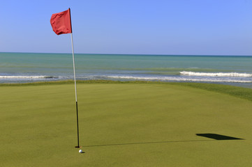 Obraz premium Golf-Grün mit Ball und Fahne am Meer