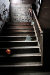 Stairwell littered with broken glass a ball and a child