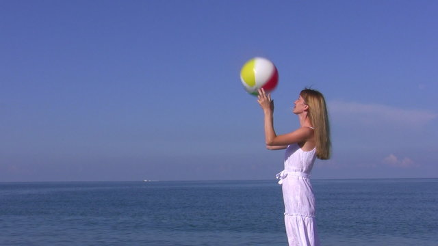 Young woman plays with ball on the beach