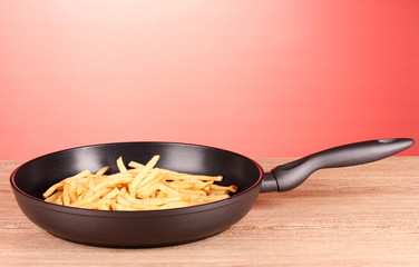 French fries in the pan on a red background