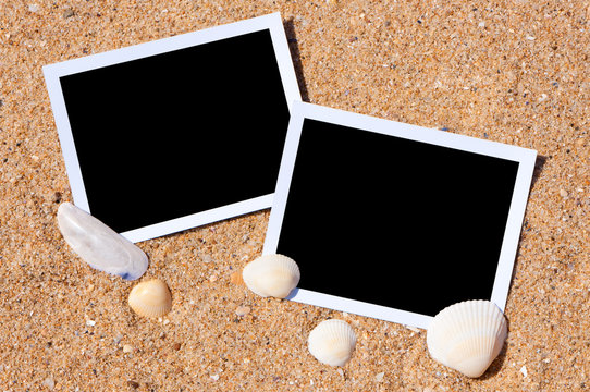 Sea shells with photos on sand background.