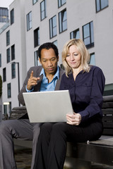 Business couple in smart casual working with notebook outdoors