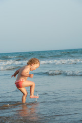 Fototapeta na wymiar Child is walking in ocean water
