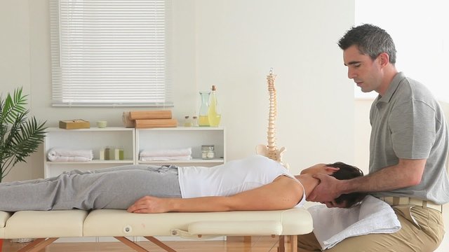 Masseur massaging the neck of a woman