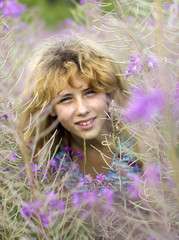 Portrait of young pretty girl looking through fireweed bushes