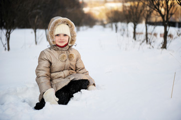 Fototapeta na wymiar Child girl in winter coat with hood plays in snow