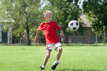 Child playing football on a soccer field