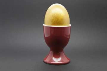 Golden Egg in a red egg cup on a black background