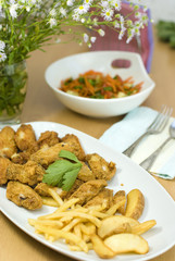 golden fried chicken and fried potatoes in a white plate