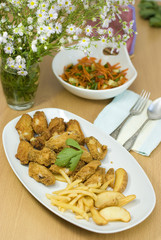 golden fried chicken and fried potatoes in a white plate