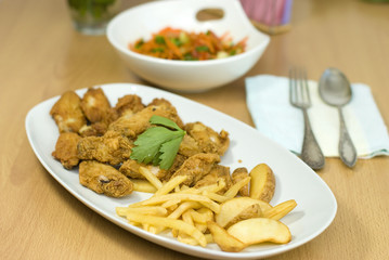golden fried chicken and fried potatoes in a white plate