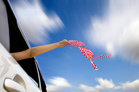 holding bikini in the air by hand of woman on fast car