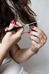 Attractive young woman is cutting her own hair
