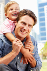 Fototapeta premium Man sitting in city park with young son