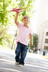 Young boy in street with toy aeroplane