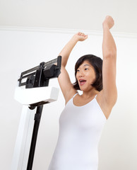 Dieting Woman on Weight Scale Cheering - 34916458