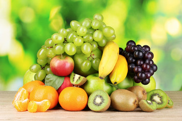 Naklejka na ściany i meble Ripe juicy fruits on wooden table on green background