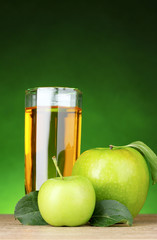 Glass of healthy fresh juice of apples on green background